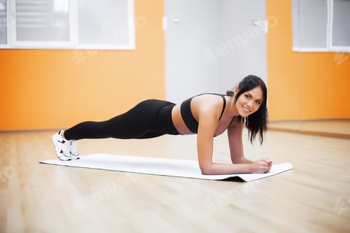 Preview: Young attractive woman doing exercises in fitness gym.