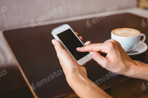 Preview: Hand of woman holding smartphone at the cafe