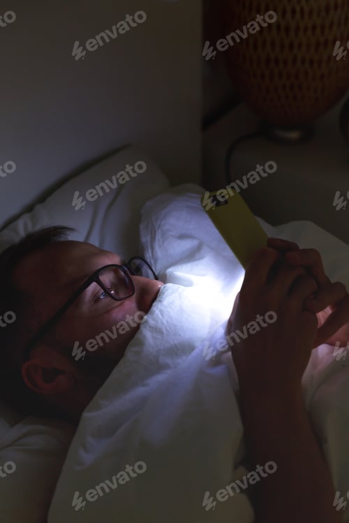 Preview: man using smartphone, lying on bed under at late night