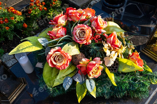 Preview: Artificial flowers and candles lie on the tombstone in the cemetery.