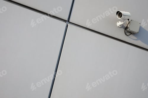 Preview: White surveillance camera built into the metal wall of the office building