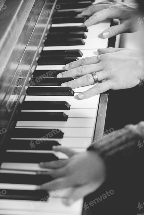 Preview: Vertical shot of a person and a child playing the piano in black and white