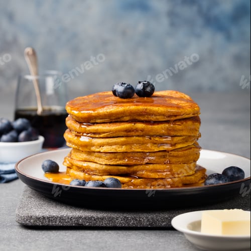 Preview: Pumpkin pancakes with maple syrup and blueberries on a plate. Grey stone background