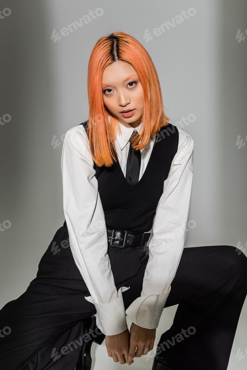 Preview: young and expressive asian woman in black and white business casual clothes looking at camera on