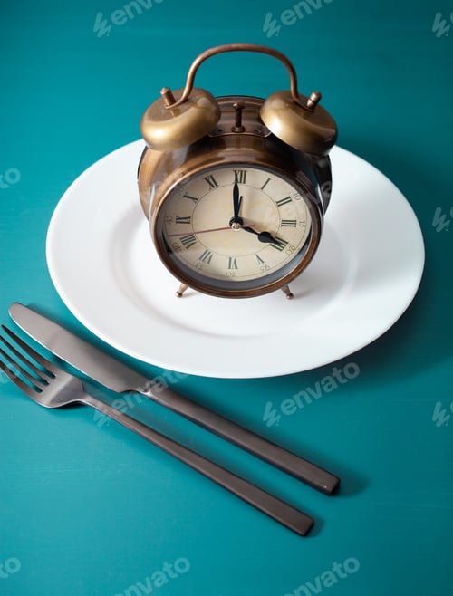 Preview: concept of intermittent fasting, ketogenic diet, weight loss. fork and knife on plate alarmclock