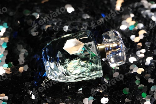 Preview: Luxury perfume in bottle on fabric with shiny sequins, closeup