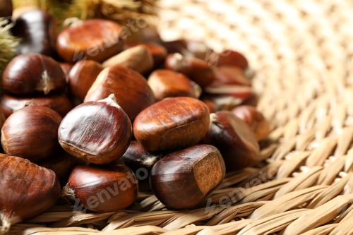 Preview: Fresh sweet edible chestnuts on wicker mat, closeup