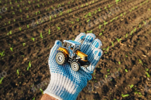 Preview: Farmer holding plastic diecast tractor farm vehicle in field