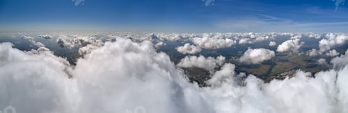 Preview: Aerial view from airplane window at high altitude of earth covered with puffy cumulus clouds