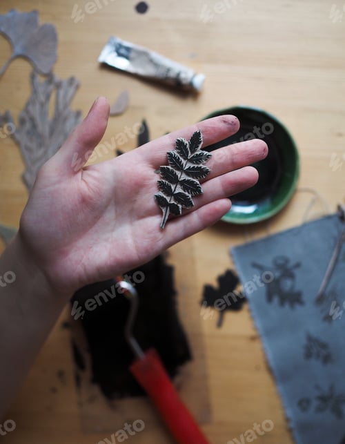 Preview: Creative handmade linocut. Close-up of female hands holding creative handmade stamp for linocut.