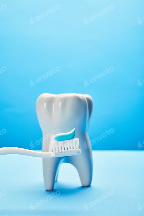 Preview: close up view of tooth model and toothbrush with paste on blue background, dental care concept