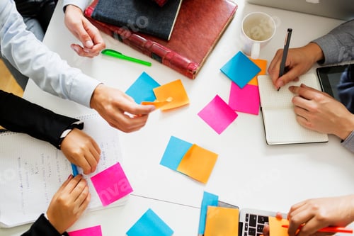 Preview: High angle view of business people analyzing notes at table