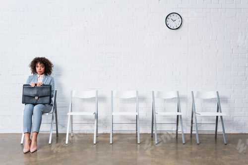 Preview: Confident businesswoman with briefcase sitting on chair and waiting