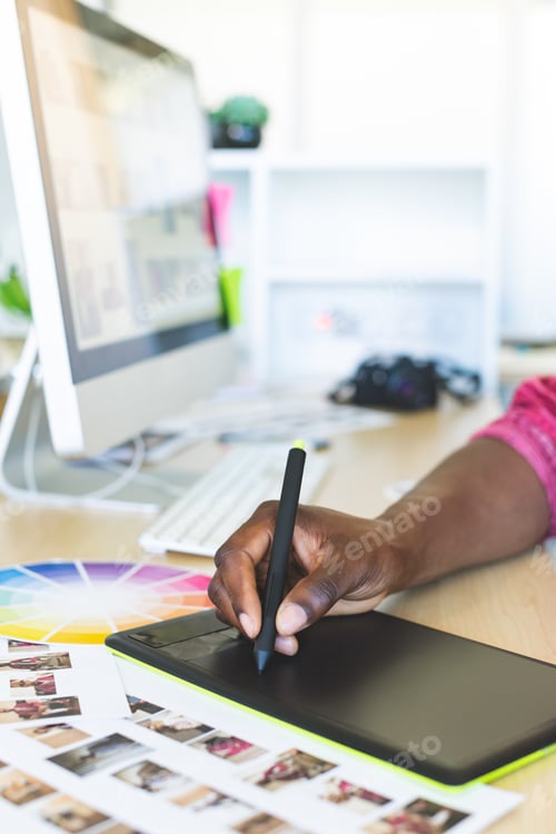Preview: Close-up of young African-American graphic designer working on graphic tablet at desk in office