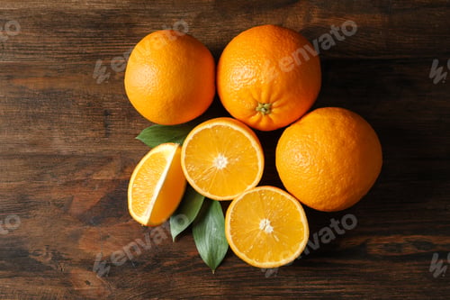 Preview: Fresh oranges with leaves on wooden background, top view