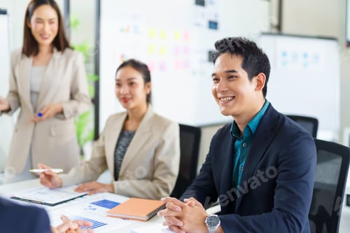 Preview: Asian businessman smiling during corporate meeting with colleagues presenting financial charts