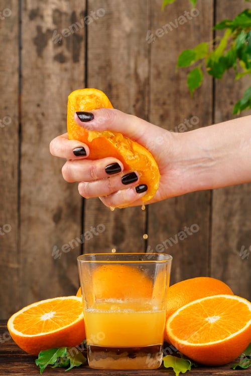 Preview: Woman hand squeezes orange juice close up