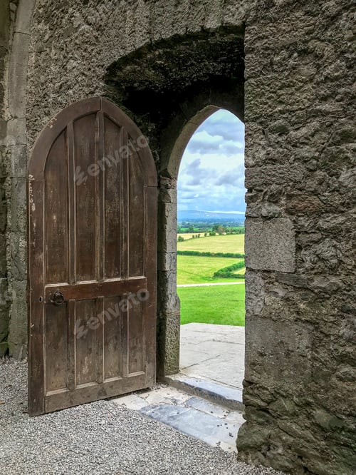 Preview: Vertical shot of a castle door revealing a beautiful view in Ireland