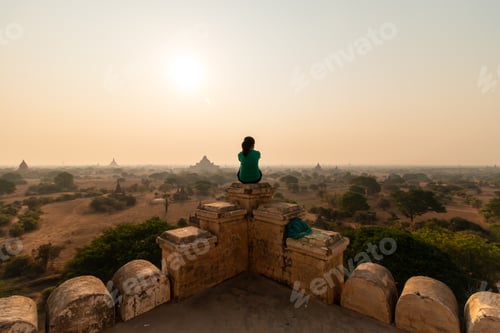 Preview: Lone person sits on top of a temple overlooking old Bagan, Myanmar