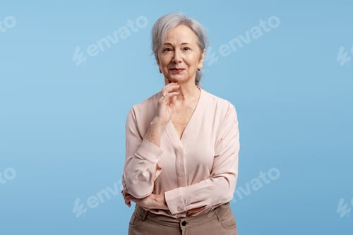 Preview: Senior woman smiling confidently, thinking with hand on chin on blue background