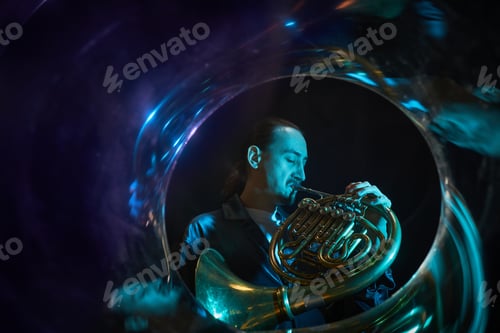 Preview: Jazzman Playing French Horn Performing Music on Stage under Blue Neon Lights