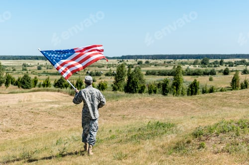 Preview: military man in uniform standing on grass and holding american flag