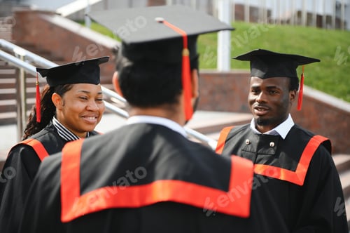 Preview: Group of happy smiling multicultural people in graduation gowns and caps with diplomas