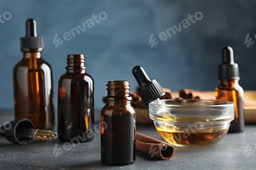 Preview: Composition with cinnamon essential oil on table against blue background
