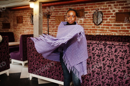 Preview: African woman in checkered violet cape posed at cafe.