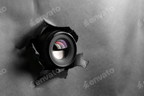 Preview: Hidden camera spying through torn hole in black paper, space for text