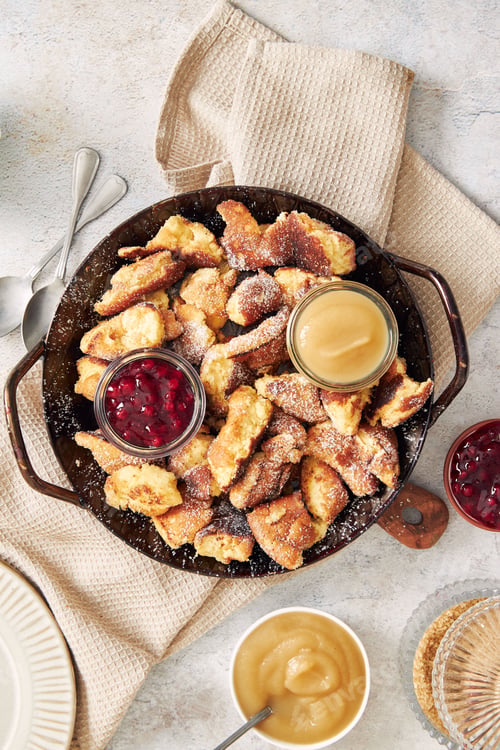 Preview: Vertical shot of kaiserschmarrn with torn pancakes, cranberries jam, and apple puree on a table