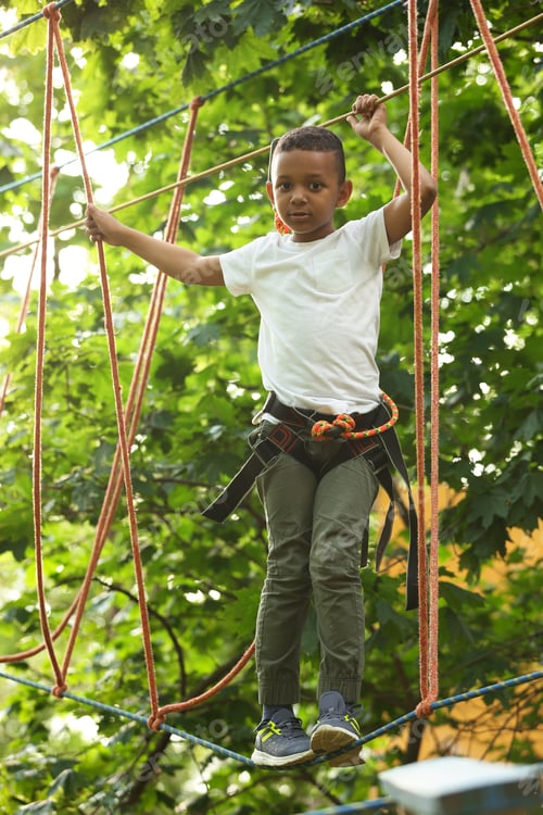 Preview: Little African-American boy climbing in adventure park. Summer camp