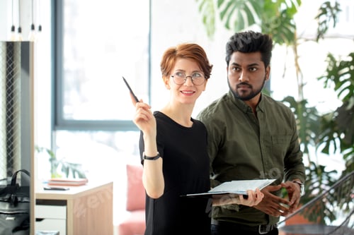Preview: business partners standing in office building and talking about deals, woman showing office