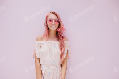 Preview: Enthusiastic girl with pink hair posing with smile in studio. Indoor photo of winsome tanned woman
