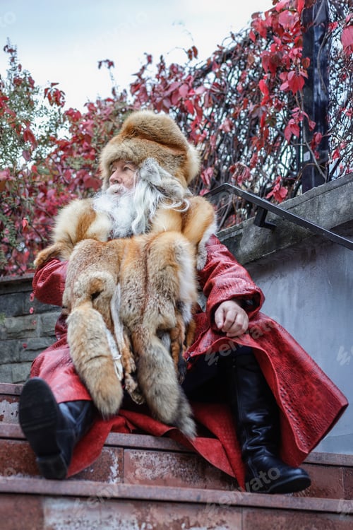 Preview: An elderly gray-haired man with a lush moustache and beard sits on the steps of the stairs and looks