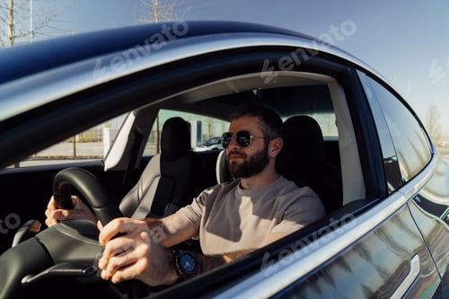 Preview: Confident man driving a modern electric car