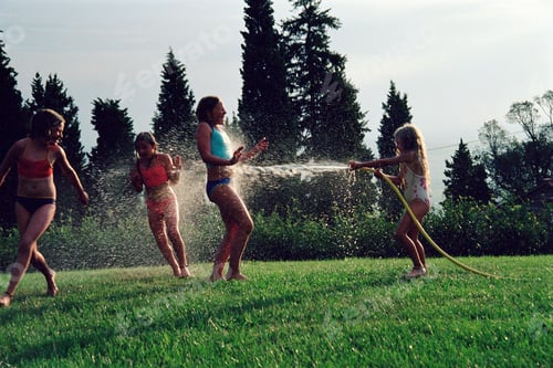 Preview: Children playing with a water hose on a sunny lawn