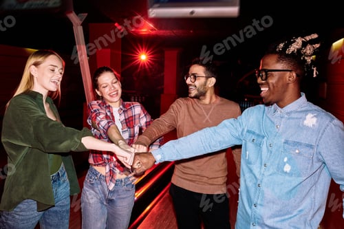 Preview: Young cheerful intercultural friends making punch bump while expressing joy