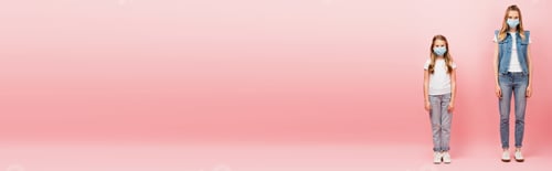 Preview: full length view of mother and daughter in denim clothes and medical masks looking at camera on