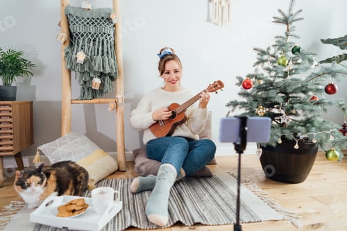 Preview: Focus on phone with young Woman playing ukulele guitar and recording Christmas music video