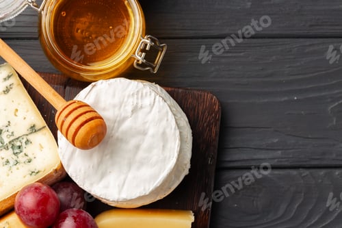 Preview: Cheese served with grapes and honey on grey surface