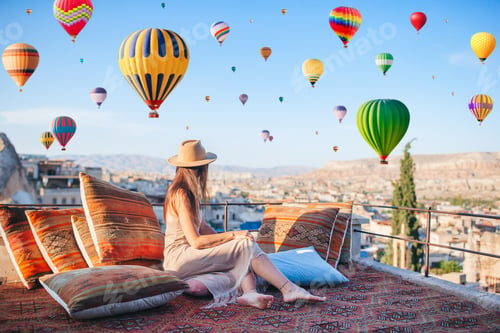 Preview: Happy young woman during sunrise watching hot air balloons in Cappadocia, Turkey