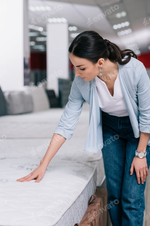 Preview: portrait of woman touching orthopedic mattress in furniture shop