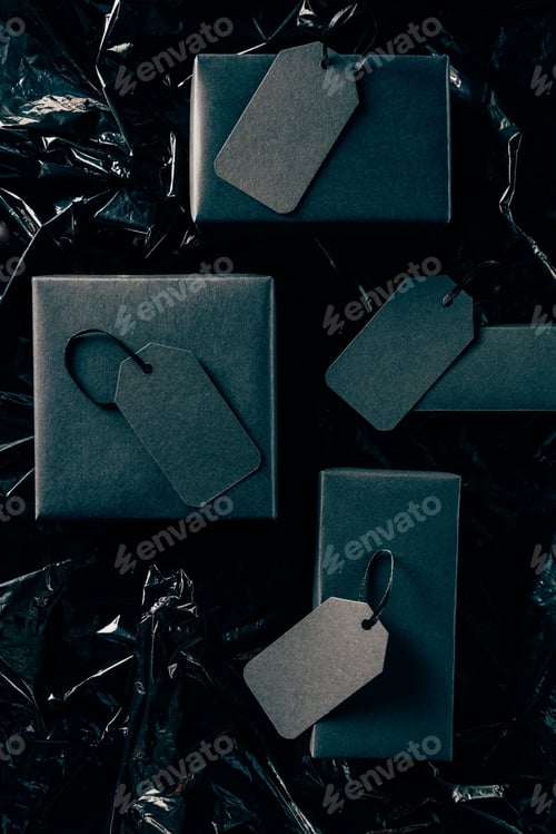 Preview: flat lay with black boxes with blank price tags on black wrapping paper backdrop, black friday