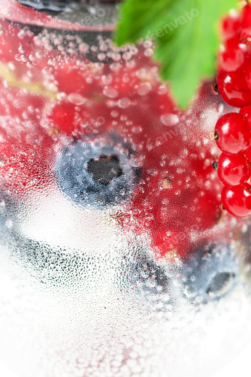 Preview: Fresh berries in soda water in a glass close-up on a white backg