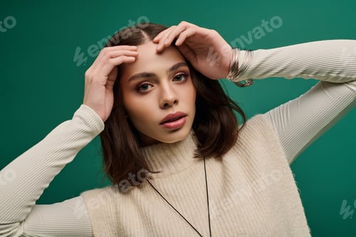 Preview: Fashion forward young woman striking a thoughtful pose against a vibrant green backdrop