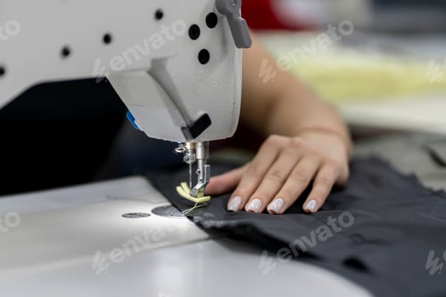 Preview: a female dressmaker working on the factory using sewing machine close up shot