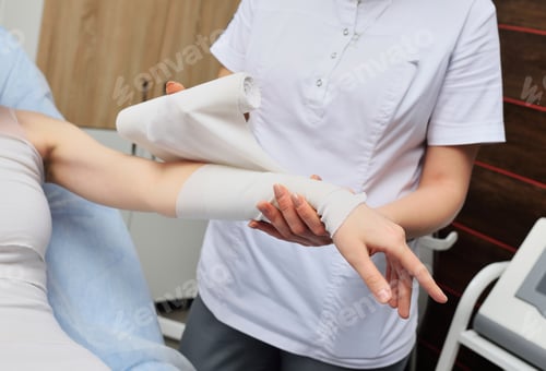 Preview: beautician wraps the patient's leg - a young pretty woman with bandages. Anti-cellulite wrapping