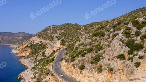 Preview: Aerial drone view of curvy asphalt road along sea and mountains.