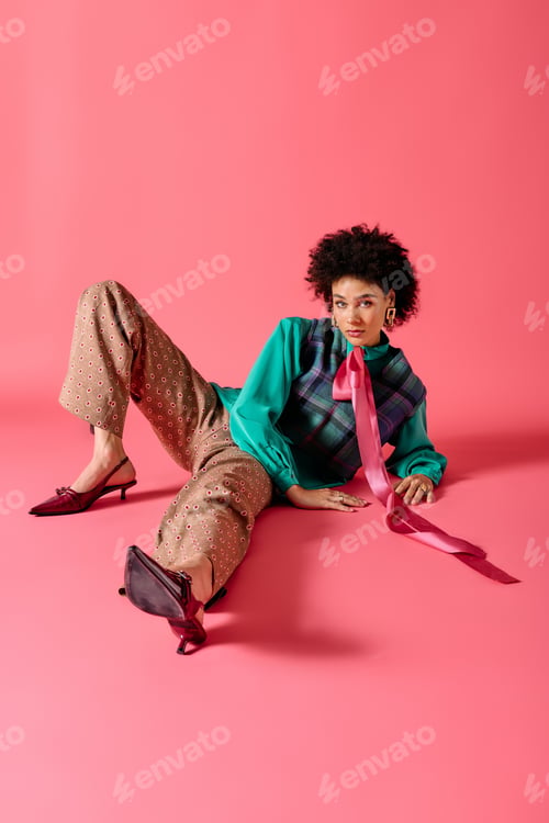 Preview: Captivating young woman showcasing unique fashion with vibrant style in a studio setting
